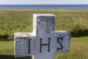 gravestone with cross and IHS letters; Notre-Dame-du-Mont-Carmel Catholic Church, Prince Edward Island, Canada