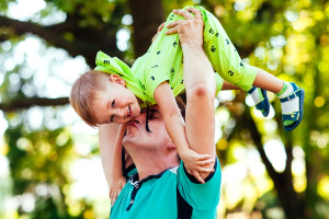 Cheerful father having fun with his little son in the park.