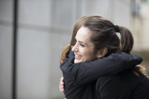Two Businesswomen hugging each other.